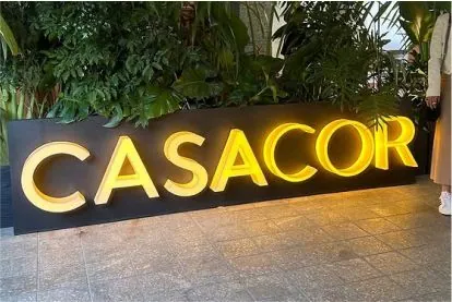 Letreiro iluminado CASACOR junto a um caminho com vegetação