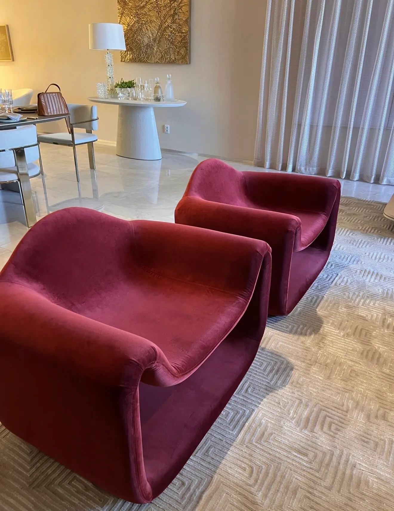Duas poltronas de veludo vermelho em um ambiente com cortinas