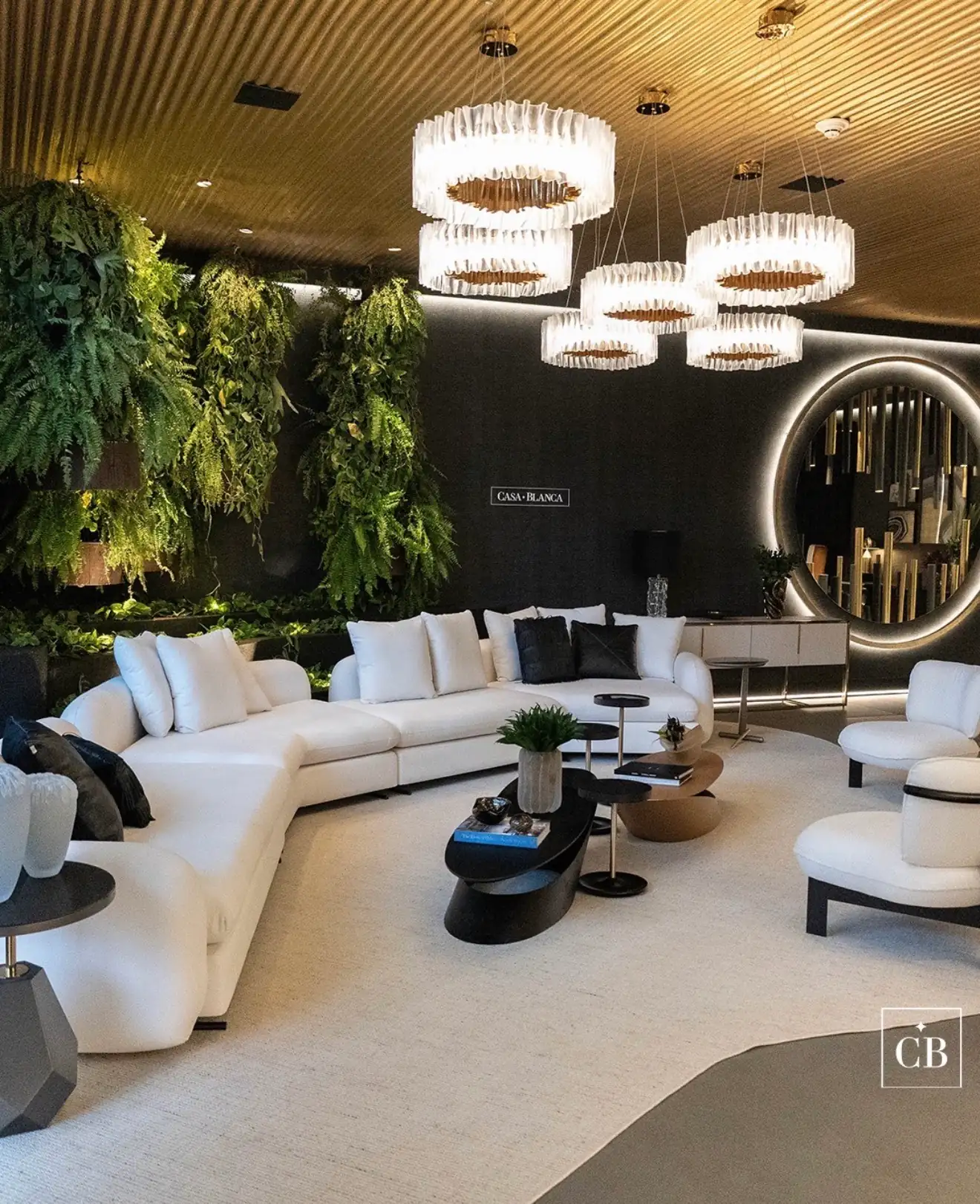Sofá claro de canto em uma sala com plantas e lustres