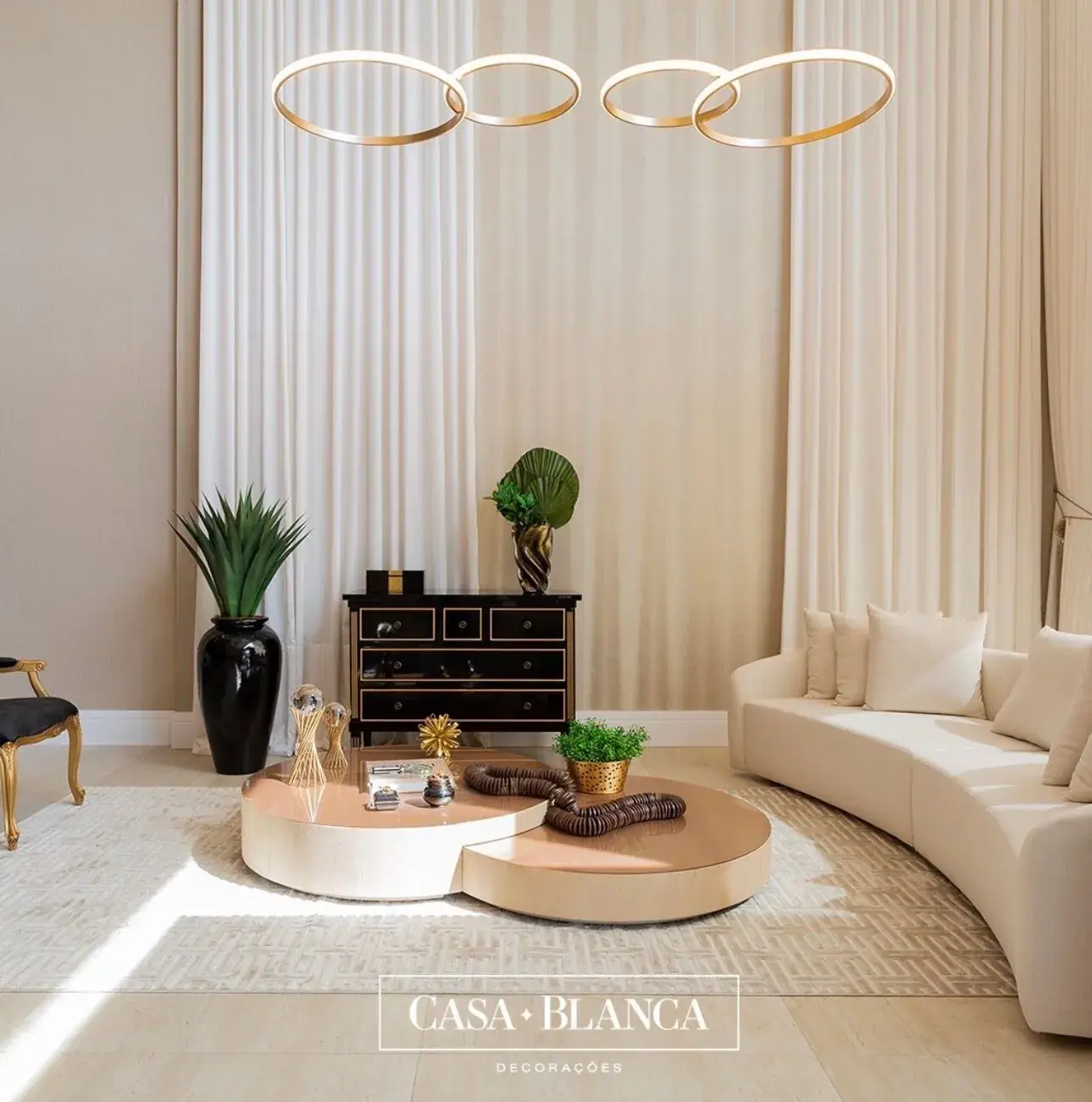 Sala com sofá claro, mesa de centro e cortinas de pregas verticais