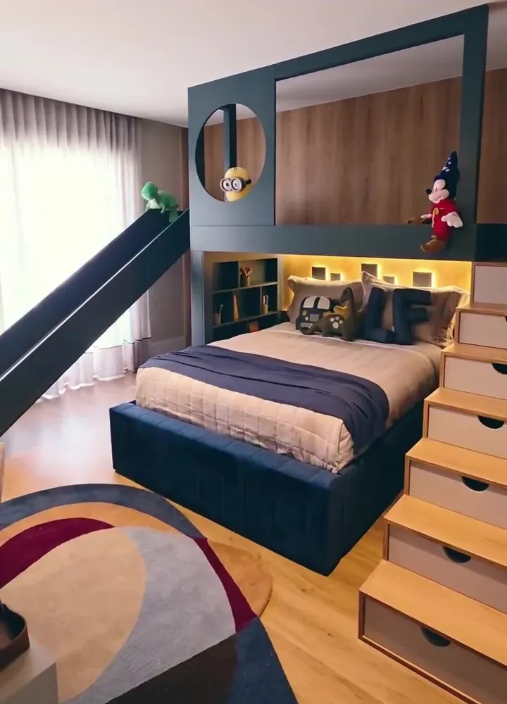 Quarto infantil azul com cama, escorregador, nichos iluminados e cortinas claras no projeto da Quadratti