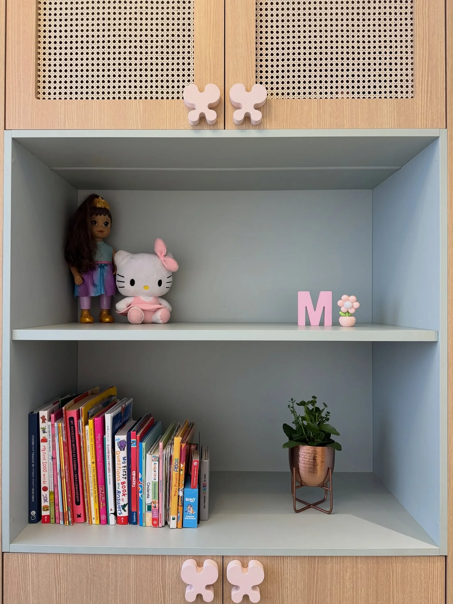 Nicho com livros e brinquedos entre portas de madeira e painéis de trama vazada