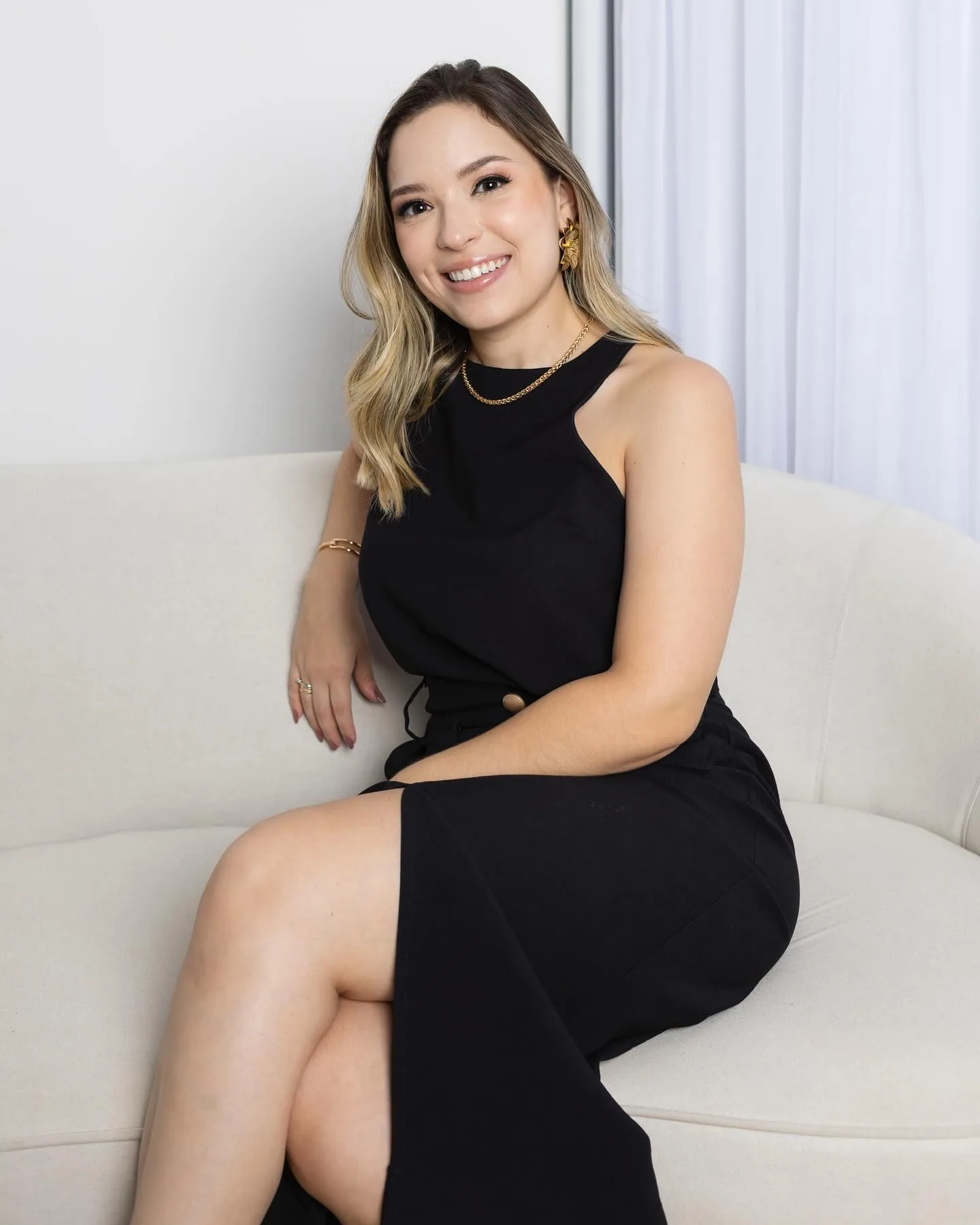 Andressa Castro sentada em um sofá claro